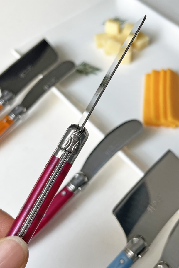 **장네론 라귀올 버터나이프 & 치즈커터 세트**는 우아하고 고급스러운 주방을 위한 필수품입니다. 11가지 다채로운 색상(로즈, 오렌지, 옐로우, 그린, 블루, 프렌치블루, 마블베이지, 아이보리, 마블브라운, 올리브, 마블블랙, 블랙)으로 제공되어 주방 인테리어에 포인트를 더합니다. 스테인리스 스틸, ABS 플라스틱, 올리브 우드 등 튼튼한 소재로 제작되어 뛰어난 내구성과 절삭력을 자랑합니다. 미세 톱니 형태의 버터나이프와 꿀벌 모양 장식, 손잡이 조각 디테일, 곡선형 그립 디자인으로 고급스러움을 더했습니다. 견고한 무게감과 정교한 절삭력으로 버터와 치즈를 부드럽게 커팅할 수 있습니다. 
