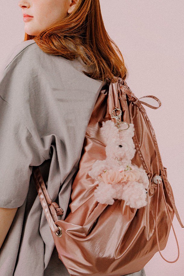 **메탈릭 스트링 백 (딥핑크)**

여성스러운 무드의 메탈릭 스트링 백입니다. 딥핑크, 실버아이보리, 카키블랙 세 가지 색상으로 출시되었으며, 미디엄 사이즈로 데이트룩, 쇼핑룩, 모임룩에 잘 어울립니다. 폴리에스터, 아크릴, 브라스, 스틸 소재로 제작되었으며, 리본과 스트링 장식이 특징입니다. 가방 내부에는 포켓이 있고, 조절 가능한 스트랩과 탈부착 리본으로 활용성을 높였습니다. 가방 모양은 사각이며, 외부 스토퍼 포켓, D링 디테일, 자수 로고, 더블 라벨, 스토퍼형 잠금 방식이 적용되었습니다.
가로 43cm, 세로 47cm, 스트랩 최대 90cm로, 넉넉한 수납 공간을 제공합니다.
