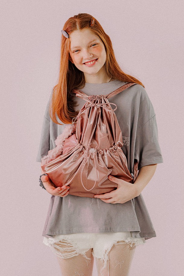 **메탈릭 스트링 백 (딥핑크)**

여성스러운 무드의 메탈릭 스트링 백입니다. 딥핑크, 실버아이보리, 카키블랙 세 가지 색상으로 출시되었으며, 미디엄 사이즈로 데이트룩, 쇼핑룩, 모임룩에 잘 어울립니다. 폴리에스터, 아크릴, 브라스, 스틸 소재로 제작되었으며, 리본과 스트링 장식이 특징입니다. 가방 내부에는 포켓이 있고, 조절 가능한 스트랩과 탈부착 리본으로 활용성을 높였습니다. 가방 모양은 사각이며, 외부 스토퍼 포켓, D링 디테일, 자수 로고, 더블 라벨, 스토퍼형 잠금 방식이 적용되었습니다.
가로 43cm, 세로 47cm, 스트랩 최대 90cm로, 넉넉한 수납 공간을 제공합니다.
