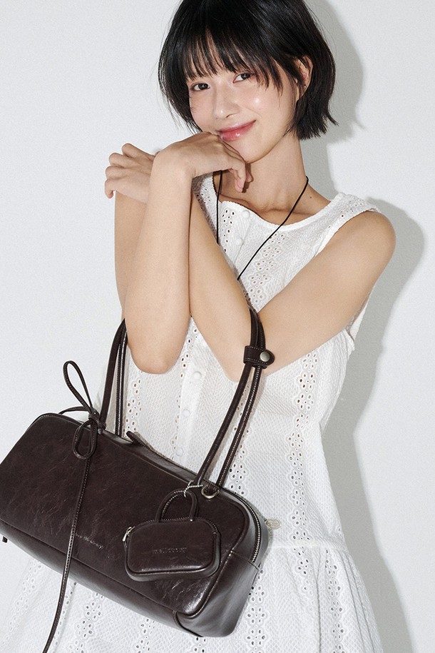 세련된 스타일을 연출하는 딥브라운 컬러의 트윈 바게트 백입니다. 폴리우레탄과 폴리에스터 소재로 제작되어 부드러운 촉감과 은은한 광택, 그레인 텍스처가 돋보입니다. 미디엄 사이즈의 사각 쉐입에 리본과 참 장식이 더해져 여성스러운 매력을 더하며, 지퍼형 잠금 방식으로 소지품을 안전하게 보관할 수 있습니다. 내부에는 지퍼 포켓과 오픈 포켓이 있어 실용적이며, 미니백 참이 포함되어 있어 포인트를 줄 수 있습니다. 데이트룩, 쇼핑룩 등 다양한 스타일에 클래식, 미니멀, 걸리시한 무드를 더해줄 아이템으로, 더스트백과 박스에 담겨 제공됩니다.
