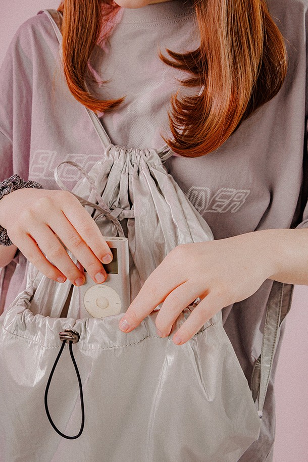 메탈릭 광택이 돋보이는 실버 컬러의 여성용 스트링 백입니다. 폴리에스터, 아크릴, 브라스, 스틸 소재로 제작되었으며, 미디엄 사이즈의 사각 쉐입에 리본, 스트링, 자수, D링 등의 디자인 장식이 더해졌습니다. 탈착 가능, 사이즈 조절, 키팅 기능과 외부/내부 포켓, 조절 가능한 스트랩, 양면 직조 라벨이 특징이며, 스토퍼나 조임용 끈으로 잠금 방식을 조절할 수 있습니다.
