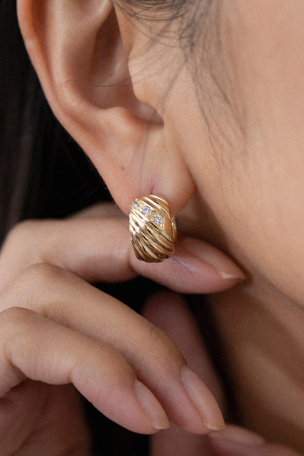 멜로디 라인 이어링 14K 골드 도금은 여성스러운 매력을 더해주는 이어링입니다. 입체적인 대각선 패턴과 중앙 큐빅지르코니아 스톤 장식이 빛 반사 효과를 주어 더욱 화려하게 빛납니다. 귀를 감싸는 곡선 실루엣 디자인은 심플하면서도 특징적인 포인트를 선사하며, 9mm x 15mm 사이즈로 데일리룩과 포멀룩에 모두 잘 어울립니다. 14K 골드 도금 마감으로 고급스러움을 더했으며, 미니멀하면서도 엘레강스한 스타일을 연출하여 모임룩이나 오피스룩에 활용하기 좋습니다.
