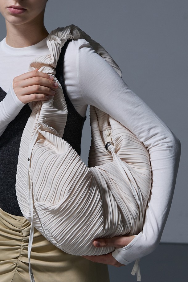 LUVITS BAG LARGE IVORY (러비츠백 라지 아이보리)는 여성스러운 데이트룩과 모임룩을 위한 숄더백입니다. 미니멀하면서도 클래식한 스타일을 추구하며, 아이보리 컬러와 무지 디자인으로 어떤 옷에도 잘 어울립니다. 라지 사이즈의 반원 모양 가방으로, 드레이핑 및 플리츠 디테일이 돋보입니다. 
