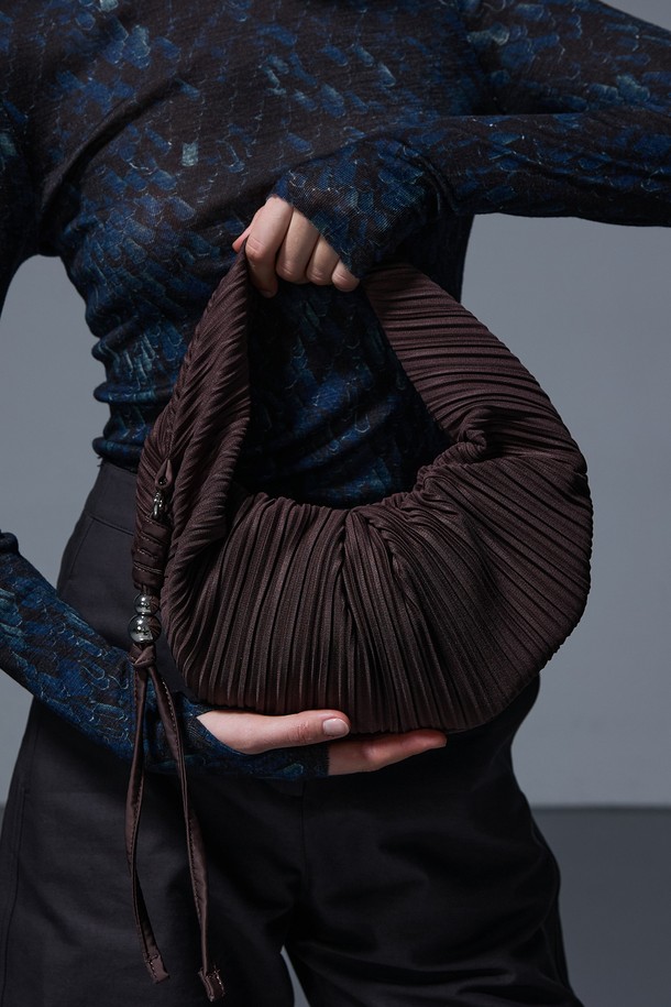 러비츠백 스몰 브라운은 여성스러운 매력을 더하는 가방입니다. 부드러운 브라운 컬러의 반원 형태에 플리츠 주름 디테일이 돋보이며, 크로스백으로 활용하여 편안하게 연출할 수 있습니다. 지퍼형 잠금 방식으로 소지품을 안전하게 보관할 수 있습니다. 미니멀, 클래식, 걸리시 스타일을 즐겨 입는 분들께 데이트룩, 모임룩에 포인트를 더하는 아이템입니다. 스몰 사이즈로, 콤팩트하면서도 세련된 스타일을 완성합니다.
