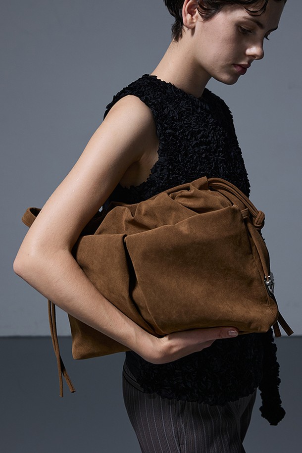 DEAR BAG LARGE SUEDE CAMEL (디어백 라지 스웨이드 카멜)은 여성용 가방으로, 부드러운 스웨이드 소재와 따뜻한 카멜 컬러가 특징입니다. 원통형 디자인에 조임용 끈으로 잠그는 방식이며, 숄더백 또는 크로스백으로 활용할 수 있습니다. 라지 사이즈로 넉넉한 수납 공간을 제공하며, 무지 디자인으로 어떤 스타일에도 잘 어울립니다. 클래식, 미니멀, 시크한 스타일을 선호하는 분들께 데이트룩, 모임룩, 여행룩에 모두 활용 가능한 실용적인 아이템입니다.
