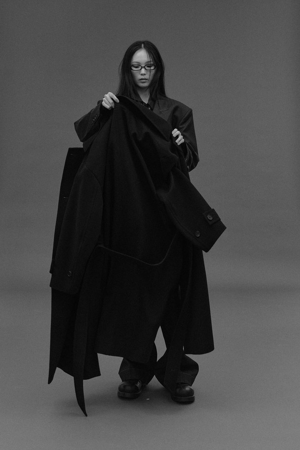 네이비 컬러의 오버사이즈드 웨이스트 벨트 코트입니다. 울과 캐시미어 혼방 소재로 제작되어 부드러운 촉감과 두꺼운 두께로 뛰어난 보온성을 자랑합니다. 클래식하고 모던한 디자인으로, 롱 기장의 더블 코트이며, 허리 부분의 웨이스트 벨트가 특징입니다. 뒷중심 벤트, 소매 밴드 버튼, 암홀 패브릭 밴드와 같은 디테일이 돋보이며, 안감은 폴리에스터와 레이온으로 마감되었습니다. 출근룩, 오피스룩, 겨울 데일리룩 등 다양한 TPO에 활용 가능하며, 미니멀하고 시크한 스타일을 연출하기 좋습니다.
