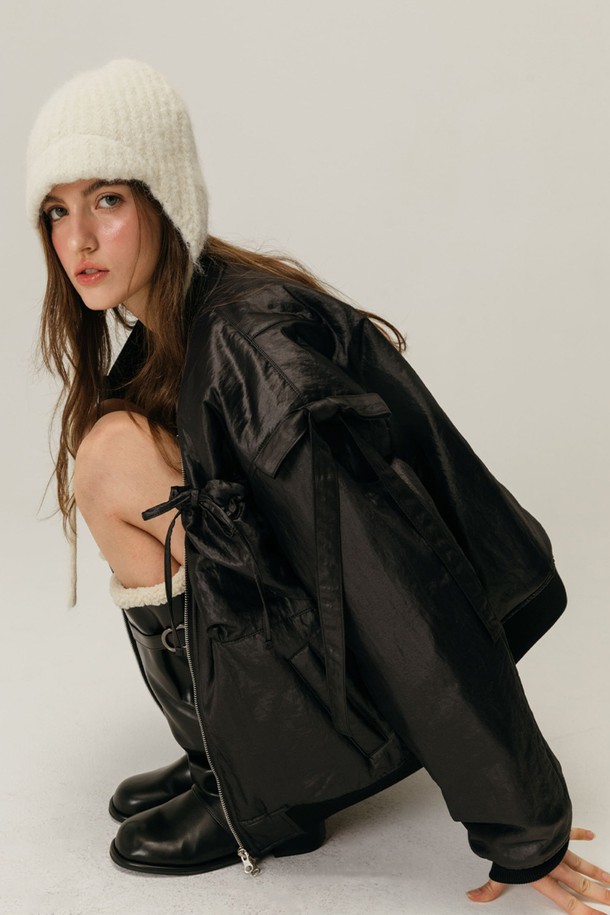 리본 봄버 재킷 / 블랙은 페미닌하면서도 캐주얼한 스타일을 연출하는 여성용 점퍼입니다. 부드러운 나일론 소재와 두꺼운 두께감으로 겨울철에도 따뜻하게 착용할 수 있습니다. 크롭 기장에 릴렉스핏과 루즈핏으로 편안함을 더했으며, 집업 스타일로 간편하게 입고 벗을 수 있습니다. 자연스러운 광택감과 리본 디테일이 돋보이며, 후드티와 레이어드하여 다양한 스타일을 연출할 수 있습니다. 데이트룩과 모임룩, 캐주얼 및 미니멀 스타일 모두 소화 가능한 활용도 높은 아이템입니다.
