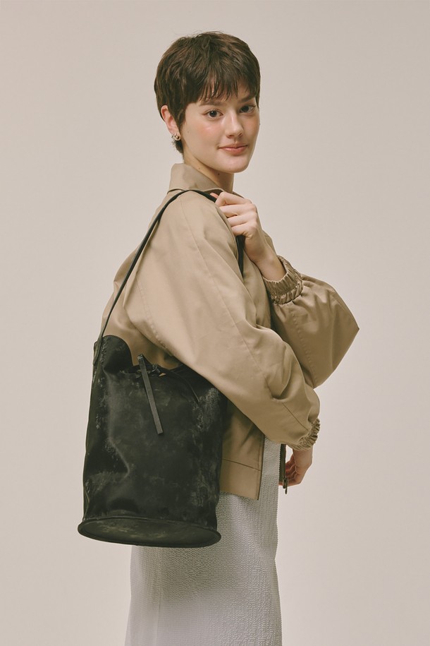 블랙 색상의 버킷 백입니다. 폴리우레탄과 폴리에스테르 소재로 제작되었으며, 미디엄 사이즈로 데이트룩, 쇼핑룩, 카페룩 등 다양한 TPO에 잘 어울립니다. 미니멀, 클래식, 캐주얼 스타일을 즐겨 입는 여성분들께 추천하며, 무지 디자인에 스트랩 탈부착이 가능하여 실용성을 더했습니다. 가방 안에는 조임용 끈이 있어 소지품을 안전하게 보관할 수 있으며, 더스트백과 금속 부자재가 포함되어 있습니다.
