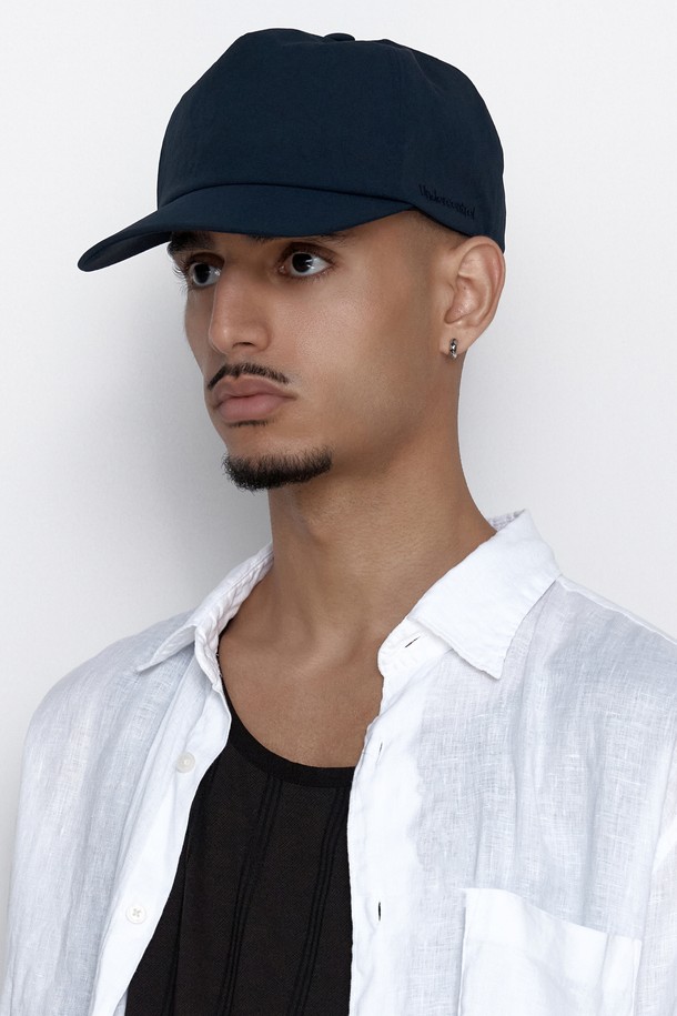 **UC 5패널 윙 캡 (네이비)**

부드러운 촉감의 나일론, 면 혼방 소재로 제작된 네이비 컬러의 캡모자입니다. 얇은 두께감으로 봄, 여름에 착용하기 좋으며, 5 패널 구조와 트러커 캡 디자인이 특징입니다. 13cm 모자 깊이와 6.5~7cm 챙 넓이로 편안한 착용감을 제공하며, 사이즈 조절이 가능합니다. 실버톤 시그니처 로고 자수와 버클 디자인으로 포인트를 더했습니다. 동네 마실룩, 산책룩, 여행룩, 캐주얼, 미니멀, 시티보이 스타일을 즐기는 분들께 추천합니다.
