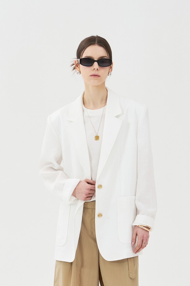 여성용 린넨 투버튼 자켓은 화이트 색상의 베이직하고 캐주얼한 스타일로, 봄, 여름철 일상복으로 적합합니다. 얇고 부드러운 린넨 소재로 제작되었으며, 오버핏에 레귤러 기장, 긴소매, 테일러드 코트 타입입니다. 6mm 어깨 패드, 하프 안감(아사), 아웃포켓, 뒷면 겹트임, 소뿔 단추 디테일이 돋보입니다.
