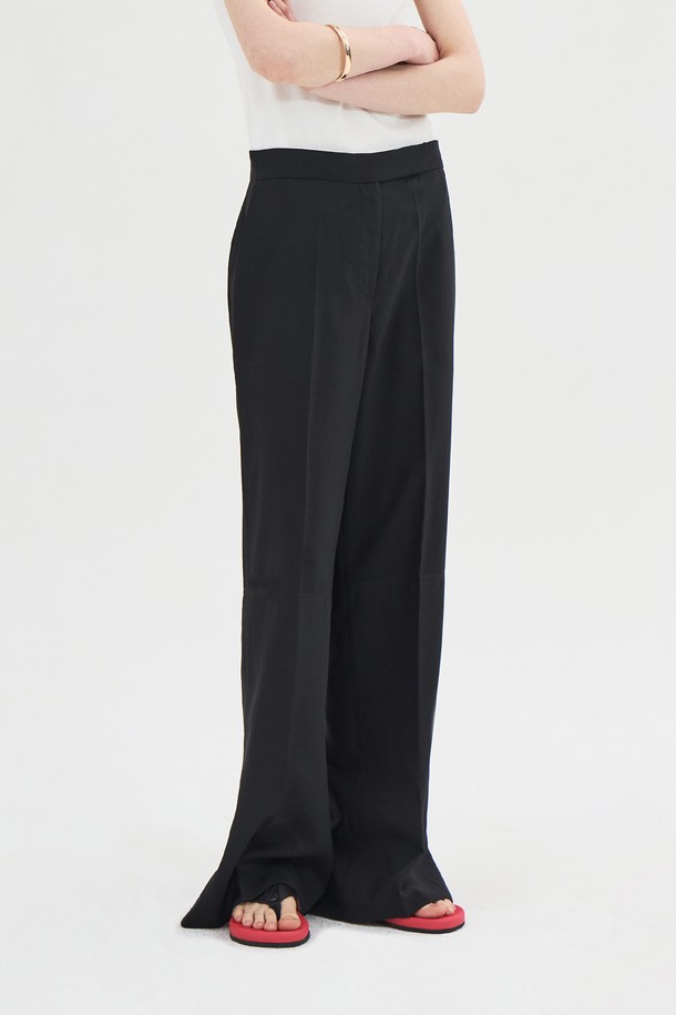 세련된 블랙 컬러의 슬릿 스트레이트 팬츠입니다. 얇은 폴리에스테르 소재로 제작되어 여름에도 시원하게 착용 가능하며, 미니멀하고 모던한 스타일을 연출합니다. 슬림핏으로 다리 라인을 슬림하게 잡아주며, 뒷면 트임 디테일과 트임 부분 배색으로 포인트를 더했습니다. 후크와 버튼 클로징, 사이드 포켓이 있으며, 안감은 없습니다.
