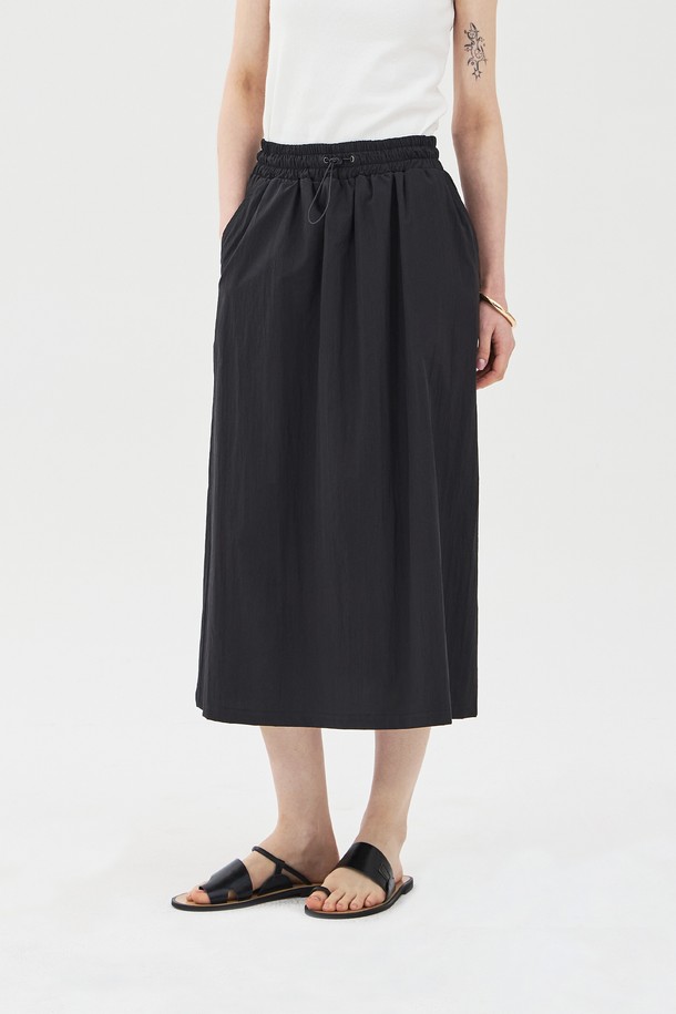 **드로우스트링 밴딩 스커트 블랙**은 여름철 캐주얼 스타일을 연출하기 좋은 롱스커트입니다. 면과 나일론 혼방 소재로 가볍고 바스락거리는 촉감을 선사하며, 핏은 여유 있게, A라인으로 떨어져 편안한 착용감을 제공합니다. 전체 밴딩 허리와 드로우스트링으로 허리 사이즈 조절이 용이하며, 사이드 포켓과 안감 처리가 되어 실용성과 비침 방지 기능까지 갖춘 실용적인 아이템입니다.
