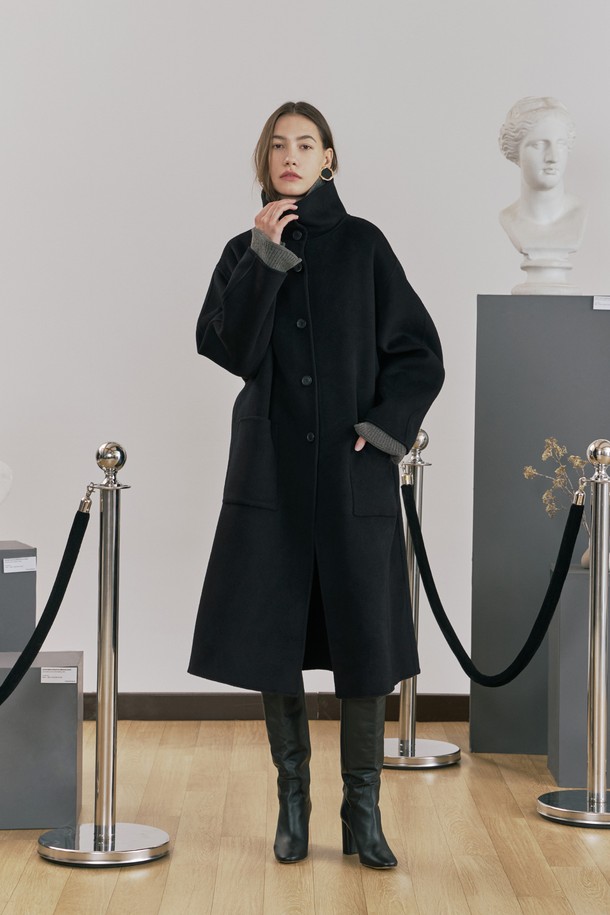 **울 핸드메이드 하이넥 롱 코트 블랙**

우아함과 미니멀함을 동시에 선사하는 여성용 울 핸드메이드 하이넥 롱 코트입니다. 부드러운 촉감의 울 소재로 제작되어 겨울철에도 따뜻하게 착용할 수 있으며, 롱 기장과 루즈핏으로 편안한 착용감을 제공합니다. 하이넥 디자인과 싱글 버튼 여밈 방식이 클래식하면서도 시크한 분위기를 연출합니다. 안감 처리가 되어 있어 고급스러운 마감과 착용감을 더했고, 아웃포켓과 소뿔 단추 디테일로 실용성을 높였습니다. 오피스룩, 출근룩, 모임룩 등 다양한 TPO에 활용 가능하며, 어떤 스타일에도 세련되게 매치할 수 있는 필수 아이템입니다.
