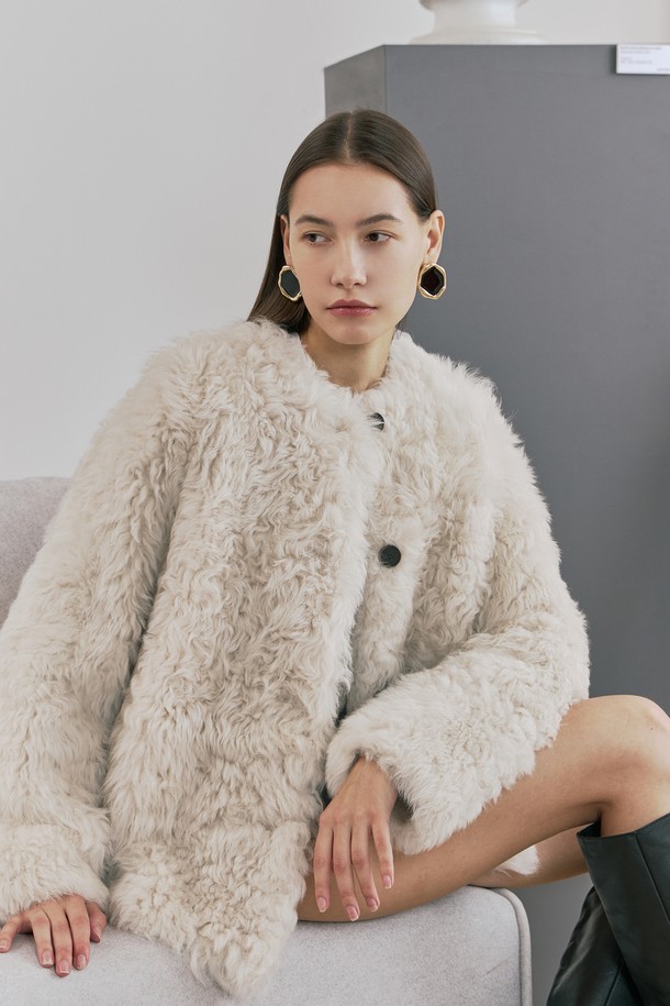 **토스카나 세미루즈 무스탕 재킷**은 부드러운 토스카나 램스킨 소재로 제작되어 뛰어난 착용감과 보온성을 자랑하는 여성용 무스탕입니다. 아이보리 컬러에 세미루즈핏으로 클래식하면서도 우아한 스타일을 연출하며, 데이트룩, 모임룩, 출근룩 등 다양한 TPO에 활용하기 좋습니다. 안감은 스웨이드로 마감되어 고급스러움을 더하고, 소뿔 단추 클로징과 사이드 포켓, 양면 스웨이드 포켓 안감, 리얼 레더 라벨 등의 디테일이 돋보입니다. 겨울철 추위 속에서도 스타일리시함을 잃지 않도록, 클래식, 미니멀, 시크한 무드를 선호하는 분들께 추천합니다. 하프 기장의 긴소매 디자인으로 어떤 룩에도 잘 어울립니다.
