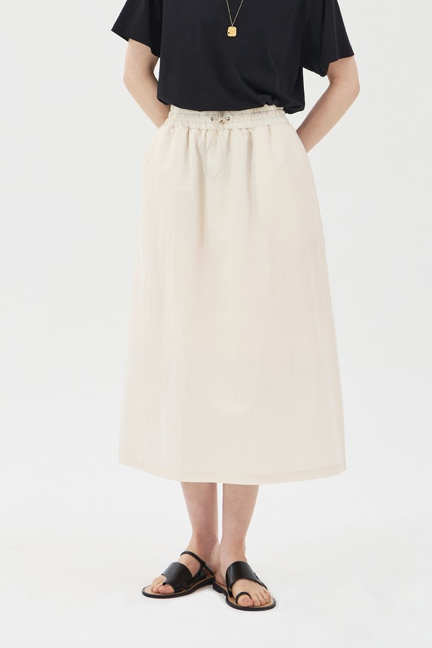 아이보리 컬러의 드로우스트링 밴딩 롱 스커트입니다. 면과 나일론 혼방 소재로 제작되어 얇고 바스락거리는 촉감이 특징이며, 여름철에도 시원하게 착용할 수 있습니다. 허리 밴딩과 드로우스트링으로 편안한 착용감을 선사하며, A라인 핏과 사이드 포켓, 안감 처리가 되어 있어 실용성을 더했습니다. 
