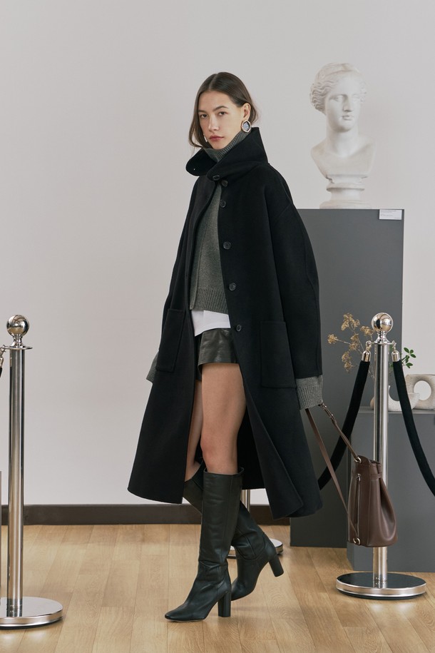 **울 핸드메이드 하이넥 롱 코트 블랙**

우아함과 미니멀함을 동시에 선사하는 여성용 울 핸드메이드 하이넥 롱 코트입니다. 부드러운 촉감의 울 소재로 제작되어 겨울철에도 따뜻하게 착용할 수 있으며, 롱 기장과 루즈핏으로 편안한 착용감을 제공합니다. 하이넥 디자인과 싱글 버튼 여밈 방식이 클래식하면서도 시크한 분위기를 연출합니다. 안감 처리가 되어 있어 고급스러운 마감과 착용감을 더했고, 아웃포켓과 소뿔 단추 디테일로 실용성을 높였습니다. 오피스룩, 출근룩, 모임룩 등 다양한 TPO에 활용 가능하며, 어떤 스타일에도 세련되게 매치할 수 있는 필수 아이템입니다.
