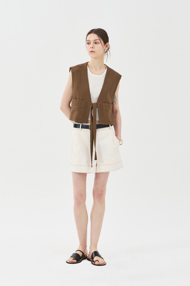 브라운 색상의 린넨 브이넥 베스트는 여름철 일상에서 클래식하고 캐주얼한 스타일을 연출하기에 좋습니다. 린넨, 레이온, 면 혼방 소재로 제작되었으며, 브이넥 디자인과 아웃포켓, 스티치 디테일, 허리 스트랩이 특징입니다. 레귤러핏과 루즈핏의 중간 형태로 민소매 디자인이며, 크롭 기장으로 제작되었습니다.

