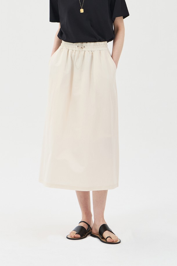 아이보리 컬러의 드로우스트링 밴딩 롱 스커트입니다. 면과 나일론 혼방 소재로 제작되어 얇고 바스락거리는 촉감이 특징이며, 여름철에도 시원하게 착용할 수 있습니다. 허리 밴딩과 드로우스트링으로 편안한 착용감을 선사하며, A라인 핏과 사이드 포켓, 안감 처리가 되어 있어 실용성을 더했습니다. 
