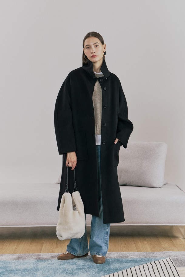 **울 핸드메이드 하이넥 롱 코트 블랙**

우아함과 미니멀함을 동시에 선사하는 여성용 울 핸드메이드 하이넥 롱 코트입니다. 부드러운 촉감의 울 소재로 제작되어 겨울철에도 따뜻하게 착용할 수 있으며, 롱 기장과 루즈핏으로 편안한 착용감을 제공합니다. 하이넥 디자인과 싱글 버튼 여밈 방식이 클래식하면서도 시크한 분위기를 연출합니다. 안감 처리가 되어 있어 고급스러운 마감과 착용감을 더했고, 아웃포켓과 소뿔 단추 디테일로 실용성을 높였습니다. 오피스룩, 출근룩, 모임룩 등 다양한 TPO에 활용 가능하며, 어떤 스타일에도 세련되게 매치할 수 있는 필수 아이템입니다.
