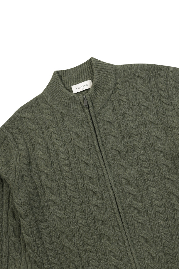 **울100 케이블 집업 가디건**은 초겨울부터 겨울까지 따뜻하게 입을 수 있는 남성용 상의입니다. 부드러운 촉감의 울 100% 소재로 제작되었으며, 레귤러 핏과 두꺼운 두께로 포근함을 더합니다. 그린과 투톤 컬러로 세련된 느낌을 주며, 케이블 패턴과 긴 소매 디자인이 특징입니다. 밑단 및 소매단 립 처리와 좌측 포켓 스웨이드 와펜 디테일이 돋보이며, 지퍼 여밈 방식으로 편안하게 착용 가능합니다. 일상, 모임, 데이트 등 다양한 TPO (Time, Place, Occasion) 에 맞춰 클래식, 미니멀, 캐주얼 스타일을 연출할 수 있는 활용도 높은 아이템입니다.
