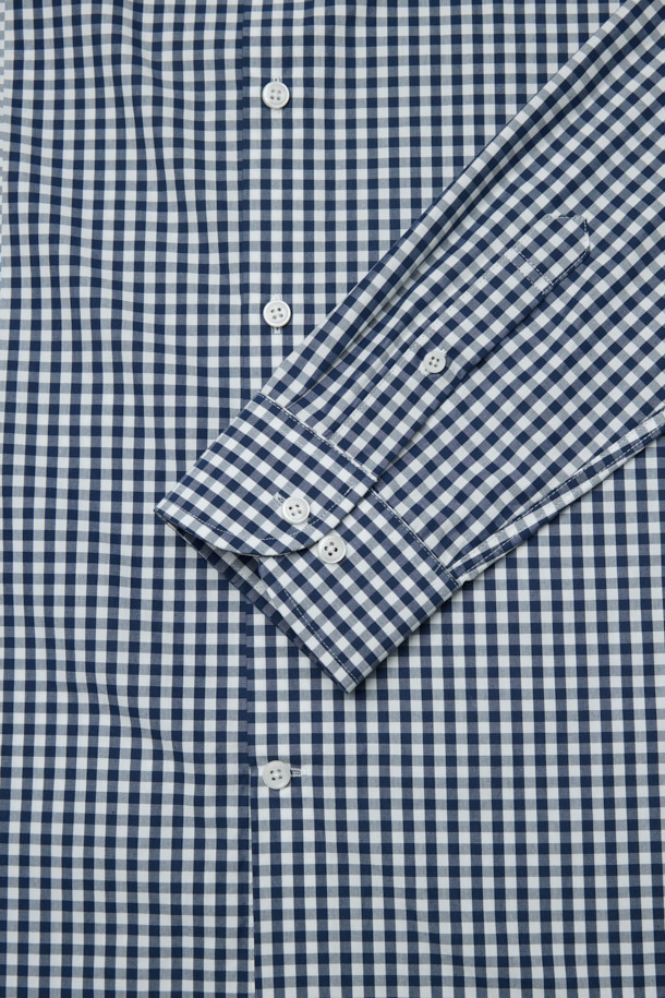 네이비와 화이트 컬러의 깅엄 체크 패턴이 돋보이는 남성용 드레스셔츠입니다. 봄, 여름, 가을 계절에 착용하기 좋으며, 레귤러핏으로 제작되어 편안한 착용감을 선사합니다. 와이드 칼라 디자인에 얇은 두께감으로 시원하게 입을 수 있으며, 롤업 가능한 긴 소매는 다양한 스타일 연출을 돕습니다. 센터 풀 버튼, 소맷단 2버튼, 칼라 심지 처리 디테일이 돋보이며, 오피스룩, 비즈니스 캐주얼, 모임룩 등 TPO에 맞춰 클래식하고 미니멀한 스타일을 연출하기 좋습니다. 면 소재로 제작되어 부드러운 촉감을 느낄 수 있습니다.
