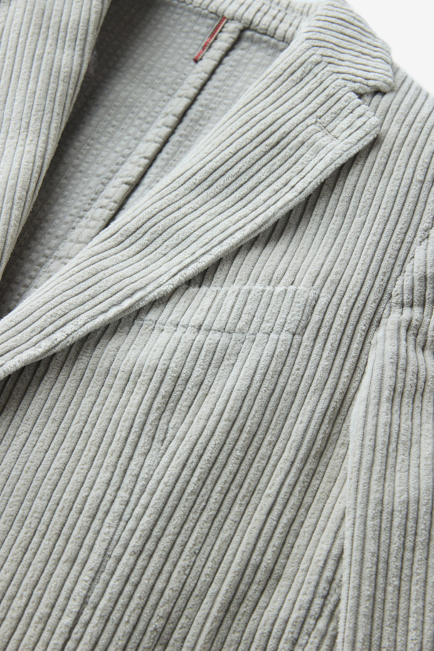 **SANTANIELLO(산타니엘로) 볼드 코듀로이 재킷**은 남성용 자켓으로, 캐주얼, 클래식, 미니멀 스타일을 모두 아우르는 매력적인 아이템입니다. 봄, 가을에 착용하기 적합하며, 출근룩으로도 활용할 수 있습니다. 그레이 컬러의 레귤러핏 자켓으로, 볼드한 코듀로이 원단과 싱글 버튼 디테일이 특징입니다. 두께감 있는 코듀로이 소재는 뻣뻣한 촉감을 선사하며, 긴 소매 기장으로 제작되었습니다. 
