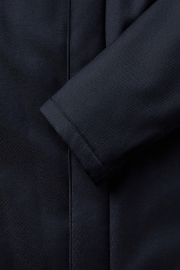 로로피아나 스톰 원단으로 제작된 남성용 구스다운 런던코트입니다. 네이비 컬러의 롱 기장 코트로, 클래식하고 포멀한 스타일을 연출합니다. 겨울철 보온을 위한 두꺼운 두께감과 방수, 방풍 기능을 갖춰 뛰어난 실용성을 자랑합니다. 레귤러핏으로 제작되었으며, 무지 디자인에 버튼 여밈 방식을 적용했습니다. 출근룩, 오피스룩, 모임룩 등 다양한 TPO에 활용 가능한, 미니멀하고 시크한 겨울철 필수 아이템입니다.
