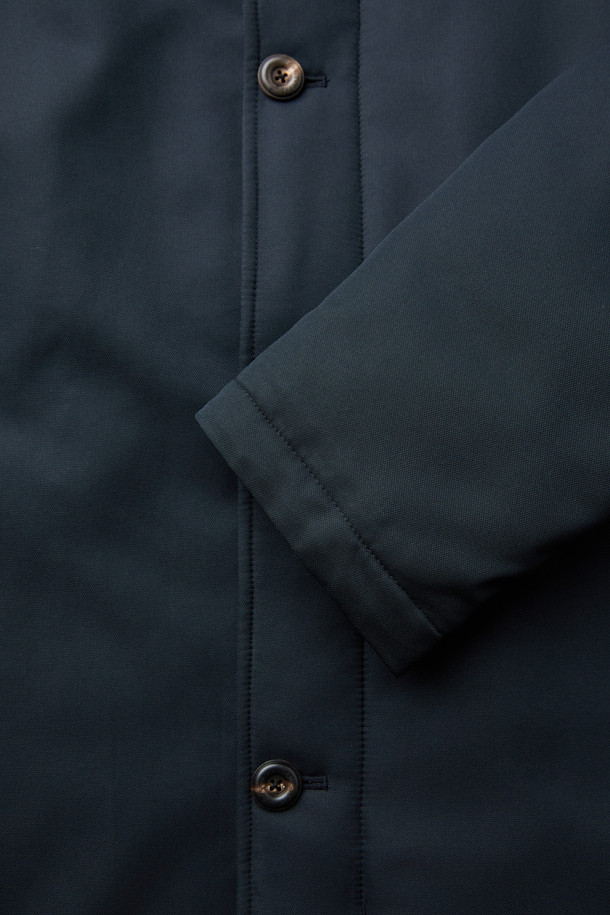 네이비 컬러의 스탠드 니트카라 구스다운 트렌치 코트입니다. 캐주얼, 클래식, 미니멀한 스타일을 모두 아우르는 디자인으로, 일상과 출근룩에 모두 활용 가능합니다. 두꺼운 두께감으로 겨울철 보온성을 높였으며, 유로피안 구스다운 충전재와 메리노 무스탕 배색으로 고급스러움을 더했습니다. 스탠드 카라와 니트 카라 디테일이 돋보이며, 레귤러핏으로 편안하게 착용할 수 있습니다. 경량 기능으로 활동성 또한 놓치지 않았습니다.
