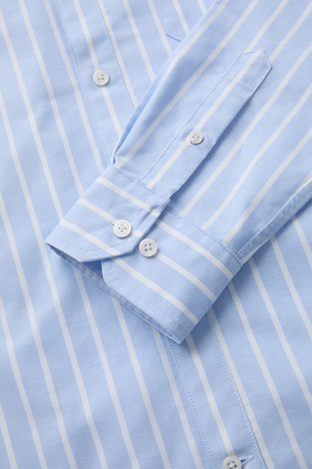 SOMELOS 볼드 스트라이프 옥스포드 셔츠는 부드러운 면 소재로 제작되어 편안한 촉감을 선사합니다. 블루와 화이트 컬러의 스트라이프 패턴이 캐주얼하면서도 베이직한 스타일을 연출하며, 봄, 여름 시즌에 활용하기 좋습니다. 옥스포드 소재 특유의 고급스러운 질감은 출근룩이나 비즈니스 캐주얼에 적합하며, 셔츠의 레귤러 기장과 긴 소매 디자인은 클래식하고 미니멀한 스타일을 완성합니다. 카라 넥 라인으로 깔끔한 인상을 주어 다양한 스타일링에 활용하기 좋습니다.

