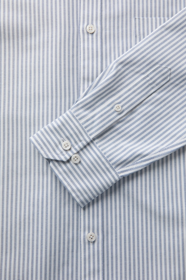SOMELOS(소멜로스) 스트라이프 옥스포드 셔츠는 블루와 화이트 컬러의 조화가 돋보이는 셔츠입니다. 면 소재의 옥스포드 원단으로 제작되어 부드러운 촉감을 선사하며, 봄, 여름 시즌에 적합합니다. 캐주얼, 베이직, 미니멀 스타일을 소화하며, 출근룩 또는 비즈니스 캐주얼로 활용하기 좋습니다. 긴소매와 레귤러 기장으로, 다양한 하의와 편안하게 매치할 수 있습니다. 촘촘한 스트라이프 패턴이 세련된 느낌을 더합니다.
