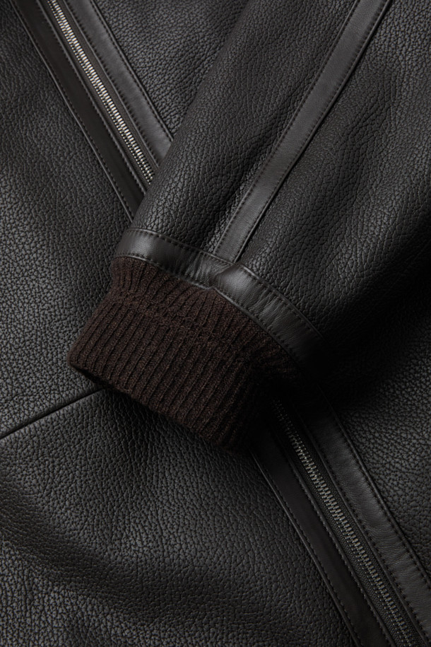 **램 엠보 G-1 구스 다운 점퍼**는 남성용 겨울 아우터로, 램스킨(가죽) 소재에 엠보싱 가공으로 고급스러움을 더했습니다. 베이직하고 캐주얼한 스타일로, 일상에서 편안하게 착용하기 좋습니다. 넉넉한 두께감과 부드러운 촉감, 소매와 밑단 니트 배색이 특징입니다. 유로피안 구스다운 충전재와 안감으로 보온성을 높였으며, 카라 퍼 디테일이 돋보이는 G-1 점퍼 스타일입니다. 집업 방식으로 간편하게 착용 가능하며, 레귤러 핏으로 제작되었습니다.
