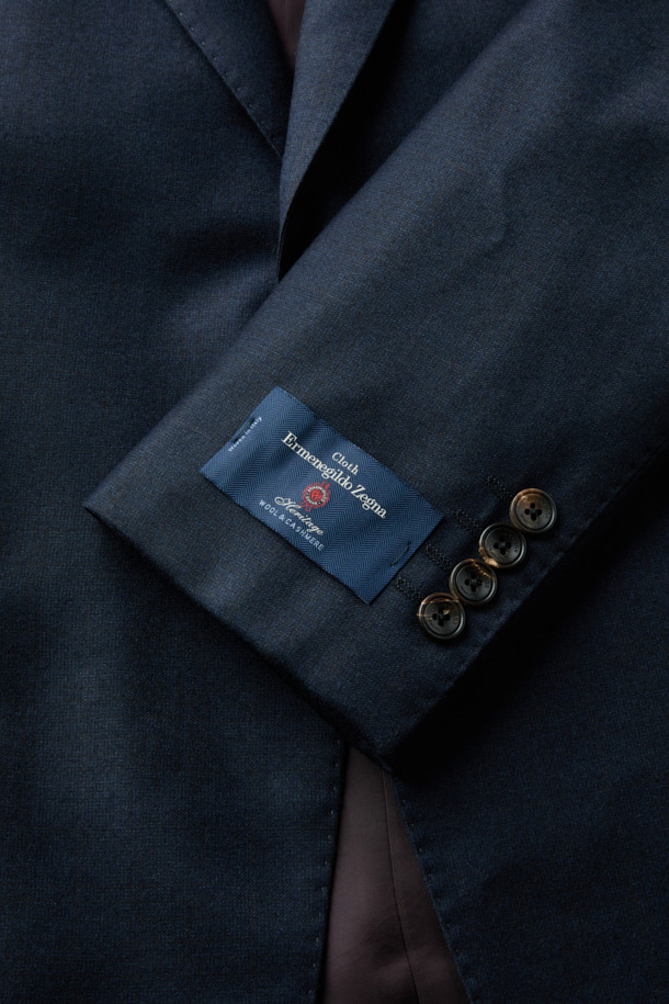 제냐 울캐시 쉐도우체크 수트 재킷 (Navy)는 포멀하고 클래식한 스타일을 추구하는 남성을 위한 겨울철 필수 아이템입니다. 부드러운 울과 캐시미어 혼방 소재로 제작되어 뛰어난 착용감과 보온성을 제공하며, 은은한 광택과 마이크로 조직감, 세미 밀드 가공으로 고급스러운 분위기를 더합니다. 네이비 컬러 바탕에 섬세한 쉐도우 체크 패턴이 적용되어 세련된 느낌을 선사하며, 레귤러핏 싱글버튼 디자인으로 오피스룩, 비즈니스 캐주얼, 출근룩 등 다양한 TPO에 활용 가능합니다. 긴 소매 기장과 두꺼운 두께감으로 겨울철에도 따뜻하고 스타일리시하게 연출할 수 있습니다.
