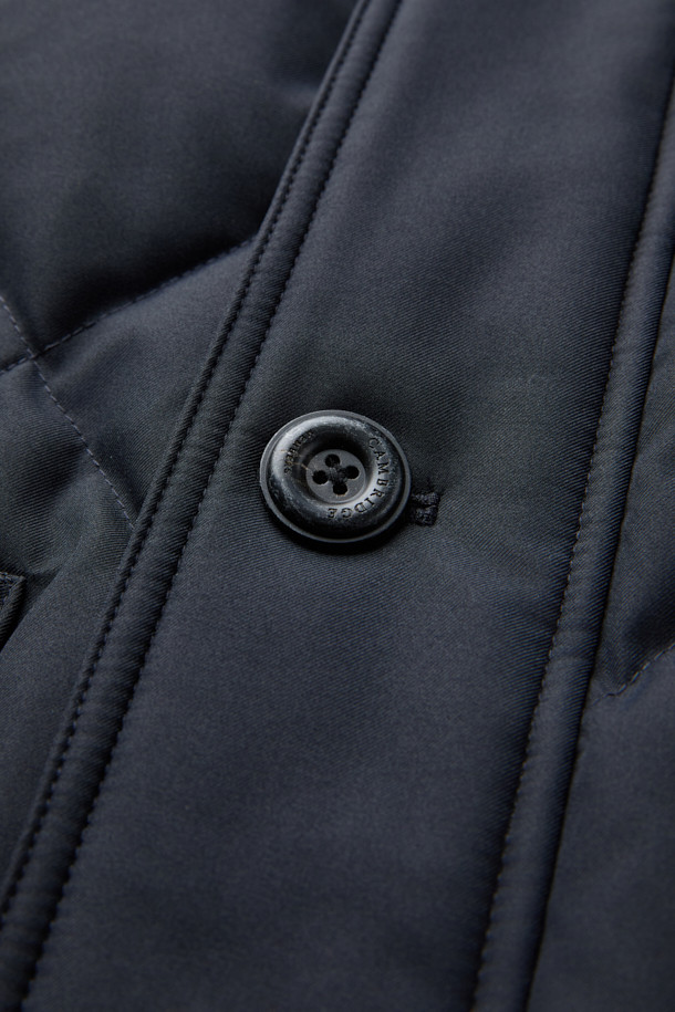 듀크 구스다운 파카는 겨울철 캐주얼 및 일상룩에 적합한 남성용 아우터입니다. 네이비 색상의 무지 디자인으로, 후드 탈착이 가능하며 경량 구스다운 충전재를 사용하여 보온성을 높였습니다. 지퍼와 버튼으로 여밀 수 있으며, 중기장 기장의 레귤러핏으로 제작되어 편안한 착용감을 제공합니다. 출근룩과 여행룩 모두 소화 가능한 미니멀하고 베이직한 스타일의 파카입니다. 
