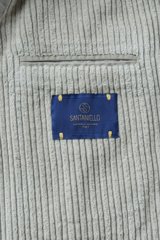 **SANTANIELLO(산타니엘로) 볼드 코듀로이 재킷**은 남성용 자켓으로, 캐주얼, 클래식, 미니멀 스타일을 모두 아우르는 매력적인 아이템입니다. 봄, 가을에 착용하기 적합하며, 출근룩으로도 활용할 수 있습니다. 그레이 컬러의 레귤러핏 자켓으로, 볼드한 코듀로이 원단과 싱글 버튼 디테일이 특징입니다. 두께감 있는 코듀로이 소재는 뻣뻣한 촉감을 선사하며, 긴 소매 기장으로 제작되었습니다. 
