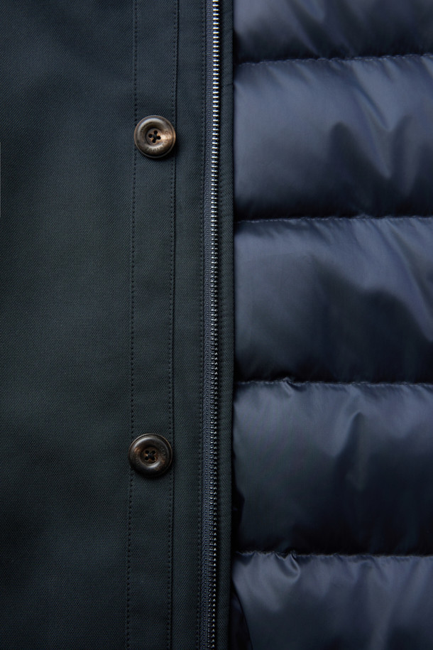 네이비 컬러의 스탠드 니트카라 구스다운 트렌치 코트입니다. 캐주얼, 클래식, 미니멀한 스타일을 모두 아우르는 디자인으로, 일상과 출근룩에 모두 활용 가능합니다. 두꺼운 두께감으로 겨울철 보온성을 높였으며, 유로피안 구스다운 충전재와 메리노 무스탕 배색으로 고급스러움을 더했습니다. 스탠드 카라와 니트 카라 디테일이 돋보이며, 레귤러핏으로 편안하게 착용할 수 있습니다. 경량 기능으로 활동성 또한 놓치지 않았습니다.
