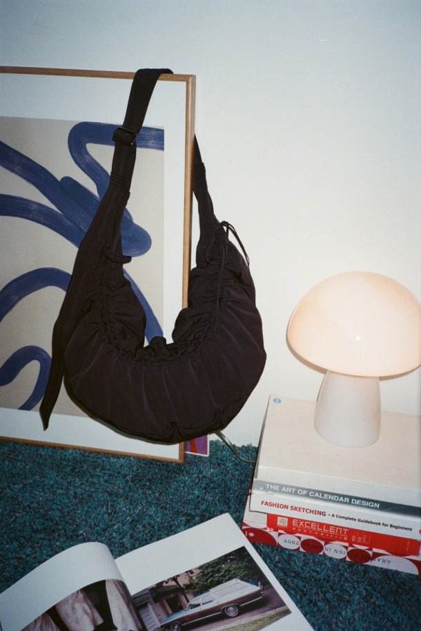 Ever Shirring Shoulder 56 (에버 셔링 숄더 56)은 부드러운 주름 텍스처가 돋보이는 여성 숄더백입니다. 나일론 소재의 미디엄 사이즈 사각 숄더백으로, 블랙 실버 컬러와 셔링 디자인이 특징입니다. 2way 방식으로 숄더 또는 크로스 형태로 착용 가능하며, 내부 포켓과 13인치 아이패드 수납이 가능하여 실용성을 높였습니다. 조절 가능한 스트랩과 블랙 실버 하드웨어 디테일이 돋보이며, 캐주얼, 미니멀, 시크 스타일을 연출하기 좋습니다. 동네 마실룩이나 쇼핑룩에 매치하여 데일리하게 활용할 수 있습니다.
