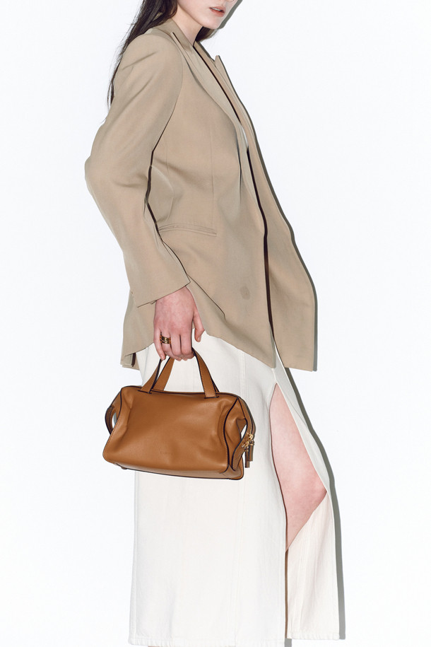 루보 토트 26은 자하 하디드의 건축물에서 영감을 받아 탄생한 여성 토트백입니다. 부드러운 네이키드 소가죽과 소가죽 소재로 제작되었으며, 브라운 컬러와 미니멀하고 클래식한 디자인이 특징입니다. 탈부착 및 길이 조절이 가능한 스트랩, 사각 형태, 골드 하드웨어 장식이 고급스러운 분위기를 더하며, 토트, 숄더, 크로스백으로 3way 연출이 가능합니다. 내부 지퍼 포켓 1개와 내부 포켓 1개가 있어 수납력을 높였으며, 오피스룩과 모임룩, 일상에서 시크하게 연출하기 좋습니다.
