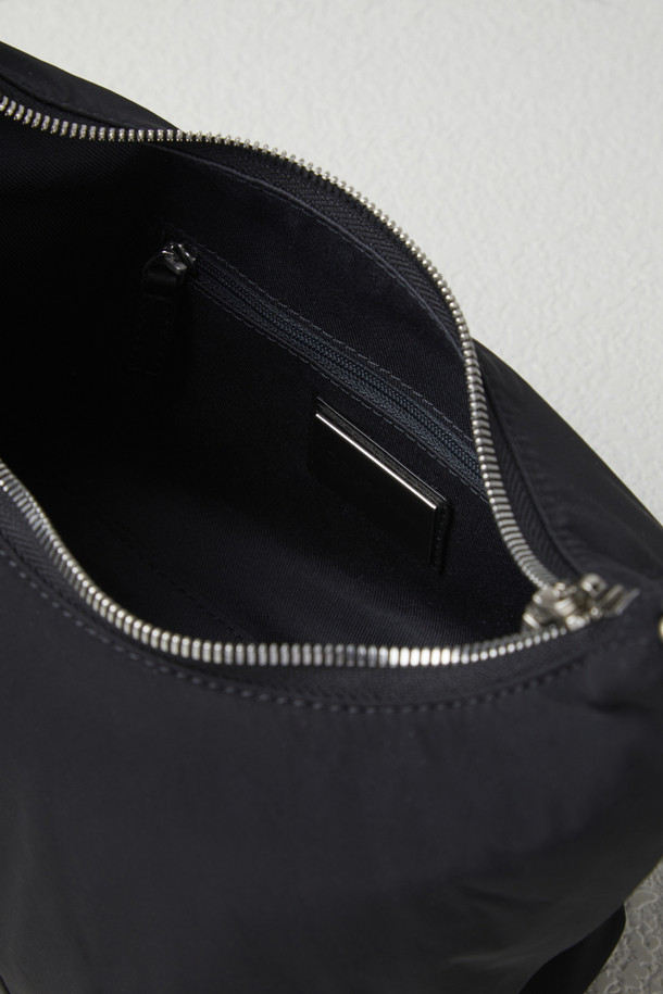 플러피 팝(Fluffy pop) 크로스 20은 여성용 크로스백으로, 미디엄 사이즈의 블랙 나일론 소재 무지 가방입니다. 반원 모양에 체인 장식이 더해져 미니멀, 클래식, 시크한 스타일을 연출합니다. 생활 방수 기능과 탈부착 가능한 스트랩으로 실용성을 높였으며, 자연스러운 주름 라인이 특징입니다. 내부에는 지퍼 포켓 1개와 일반 포켓 1개가 있어 수납이 용이하며, 브라스 소재 하드웨어가 고급스러움을 더합니다. 출근룩, 모임룩, 데이트룩 등 다양한 TPO에 활용 가능합니다.
