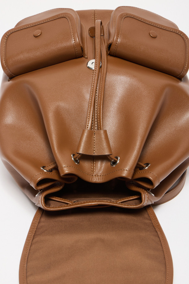 버터니 백팩 24는 부드러운 소가죽 소재의 여성 가방입니다. 브라운 컬러의 무지 디자인으로, 버튼, 지퍼, 드로우스트링 디테일이 돋보이며, 미디엄 사이즈의 사각형 쉐입을 갖추었습니다. 외부 오픈 포켓 2개, 지퍼 포켓 1개, 내부 백패널 오픈 포켓 1개로 실용적인 수납력을 제공하며, 조절 가능한 스트랩으로 편안한 착용감을 선사합니다. 글로시 마감으로 고급스러움을 더하여 데이트룩, 쇼핑룩, 카페룩 등 다양한 TPO에 클래식, 미니멀, 시크 스타일을 연출하기 좋습니다.
