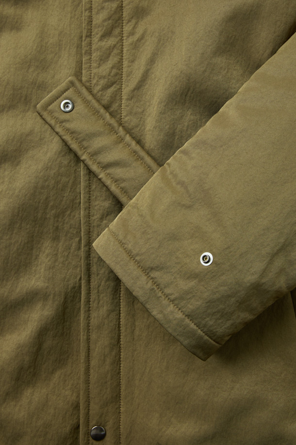 [HED MAYNER] 골드 오버사이즈 핏 패딩 파카는 겨울철 일상과 출근룩에 모두 잘 어울리는 남성용 아우터입니다. 모던한 무드의 무지 디자인에 오버핏으로 제작되어 편안하면서도 세련된 스타일을 연출합니다. 두꺼운 두께감의 나일론 소재와 퀼팅 안감으로 보온성을 높였으며, 구조적인 패턴과 소매 스트랩 디테일이 특징입니다. 집업 스타일로 간편하게 착용 가능하며, 내부 및 외부 포켓과 포켓 하단 포인트 라벨이 실용성을 더합니다. 미니멀, 클래식, 시크한 스타일을 즐기는 분들께 추천하는 패딩입니다.
