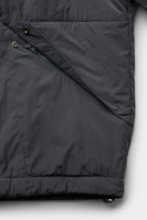 다크그레이 컬러의 탈부착 패딩 재킷입니다. 나일론과 폴리에스테르 혼방 소재로 제작되어 겨울철에도 따뜻하게 착용 가능하며, 오버핏으로 편안한 착용감을 선사합니다. 탈부착 가능한 소매 디자인으로 다양한 스타일 연출이 용이하며, 하이넥 디자인과 YKK 2-Way 지퍼, 스트링, 스토퍼 디테일이 특징입니다. 캐주얼, 미니멀, 시티보이 룩에 잘 어울리며, 출근룩과 여행룩 모두 소화 가능한 실용적인 아이템입니다.
