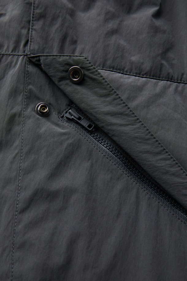 다크그레이 컬러의 탈부착 패딩 재킷입니다. 나일론과 폴리에스테르 혼방 소재로 제작되어 겨울철에도 따뜻하게 착용 가능하며, 오버핏으로 편안한 착용감을 선사합니다. 탈부착 가능한 소매 디자인으로 다양한 스타일 연출이 용이하며, 하이넥 디자인과 YKK 2-Way 지퍼, 스트링, 스토퍼 디테일이 특징입니다. 캐주얼, 미니멀, 시티보이 룩에 잘 어울리며, 출근룩과 여행룩 모두 소화 가능한 실용적인 아이템입니다.
