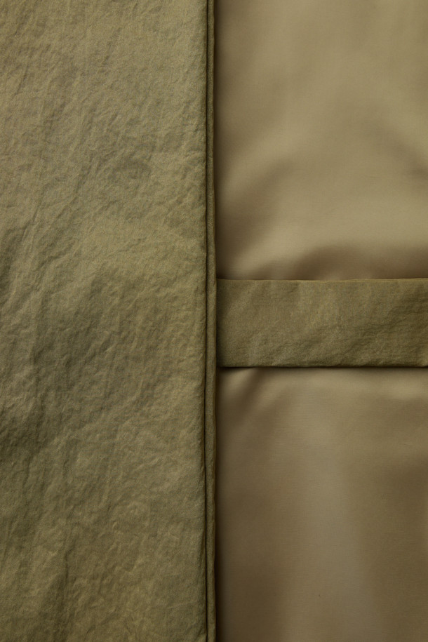 [HED MAYNER] 골드 백 슬릿 로브 코트는 남성용 아우터로, 가을과 겨울에 착용하기 좋습니다. 미니멀하고 모던한 스타일의 이 로브 코트는 부드러운 촉감의 나일론 소재와 넉넉한 오버핏으로 제작되었습니다. 등 부분의 넥 슬릿 디테일과 벨트 허리 슬릿 구조가 특징이며, 내부에는 패딩 안감과 외부 및 내부 포켓이 있어 실용성을 더했습니다. 광택감 있는 골드 컬러는 출근룩이나 모임룩에 시크하고 클래식한 분위기를 연출합니다.
