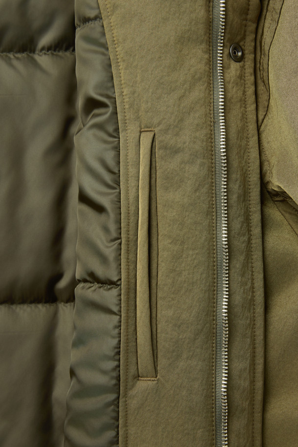 [HED MAYNER] 골드 오버사이즈 핏 패딩 파카는 겨울철 일상과 출근룩에 모두 잘 어울리는 남성용 아우터입니다. 모던한 무드의 무지 디자인에 오버핏으로 제작되어 편안하면서도 세련된 스타일을 연출합니다. 두꺼운 두께감의 나일론 소재와 퀼팅 안감으로 보온성을 높였으며, 구조적인 패턴과 소매 스트랩 디테일이 특징입니다. 집업 스타일로 간편하게 착용 가능하며, 내부 및 외부 포켓과 포켓 하단 포인트 라벨이 실용성을 더합니다. 미니멀, 클래식, 시크한 스타일을 즐기는 분들께 추천하는 패딩입니다.
