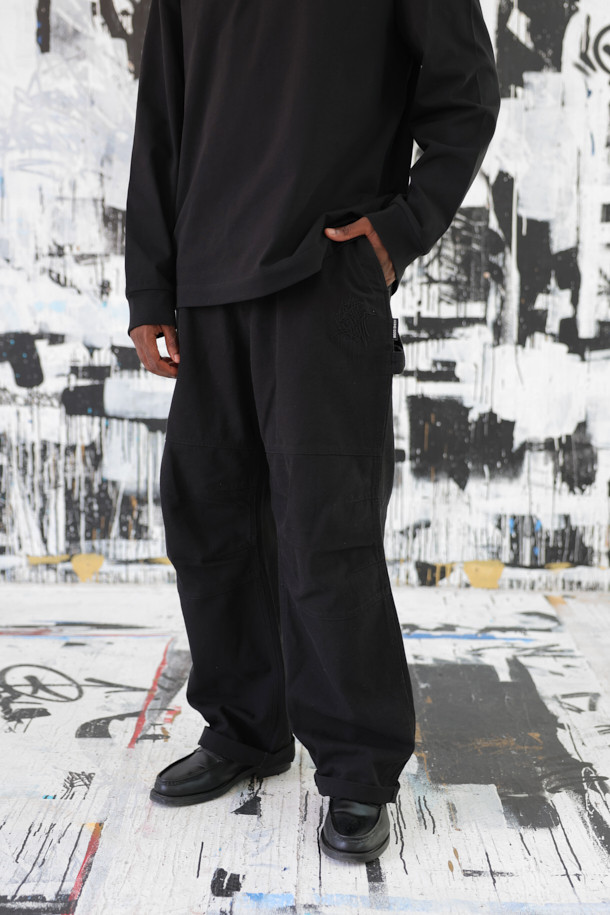 **BISCO SMITH (비스코 스미스) 블랙 코튼 카펜터 팬츠**

BISCO SMITH (비스코 스미스) 블랙 코튼 카펜터 팬츠는 스트릿 스타일을 기반으로, 워크웨어와 캐주얼 무드를 더한 긴 기장의 와이드핏 면 바지입니다. 무릎 부분의 파라슈트 레이어 디자인과 BISCO SMITH 'AsAbove' 자수 디테일이 특징입니다. 고밀도 코튼 소재를 사용하여 튼튼하며, 두꺼운 두께감으로 제작되었습니다. 편안하면서도 개성 있는 스타일을 연출하기에 좋은 아이템입니다.
