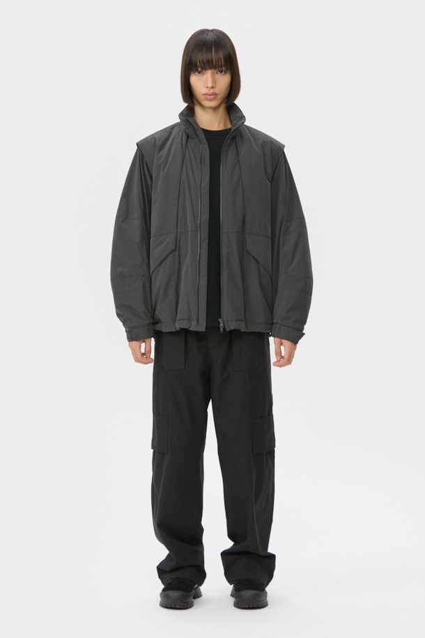 다크그레이 컬러의 탈부착 패딩 재킷입니다. 나일론과 폴리에스테르 혼방 소재로 제작되어 겨울철에도 따뜻하게 착용 가능하며, 오버핏으로 편안한 착용감을 선사합니다. 탈부착 가능한 소매 디자인으로 다양한 스타일 연출이 용이하며, 하이넥 디자인과 YKK 2-Way 지퍼, 스트링, 스토퍼 디테일이 특징입니다. 캐주얼, 미니멀, 시티보이 룩에 잘 어울리며, 출근룩과 여행룩 모두 소화 가능한 실용적인 아이템입니다.
