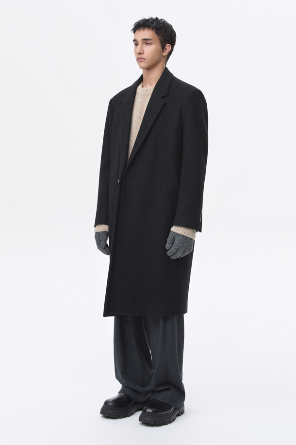 남성용 블랙 오버사이즈 핏 노치드 라펠 코트입니다. 가을, 겨울 시즌에 어울리는 두꺼운 두께감으로, 울, 나일론, 캐시미어 혼방 소재로 제작되어 부드러운 촉감과 보온성을 제공합니다. 미니멀, 클래식 스타일을 기반으로 하여 출근룩, 오피스룩, 모임룩 등 다양한 TPO에 활용 가능합니다. 싱글 버튼 여밈 방식과 롱 기장, 긴 소매 디자인으로 시크한 매력을 더하며, 오버핏으로 편안한 착용감을 선사합니다.
