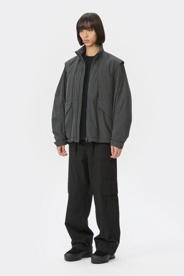 다크그레이 컬러의 탈부착 패딩 재킷입니다. 나일론과 폴리에스테르 혼방 소재로 제작되어 겨울철에도 따뜻하게 착용 가능하며, 오버핏으로 편안한 착용감을 선사합니다. 탈부착 가능한 소매 디자인으로 다양한 스타일 연출이 용이하며, 하이넥 디자인과 YKK 2-Way 지퍼, 스트링, 스토퍼 디테일이 특징입니다. 캐주얼, 미니멀, 시티보이 룩에 잘 어울리며, 출근룩과 여행룩 모두 소화 가능한 실용적인 아이템입니다.
