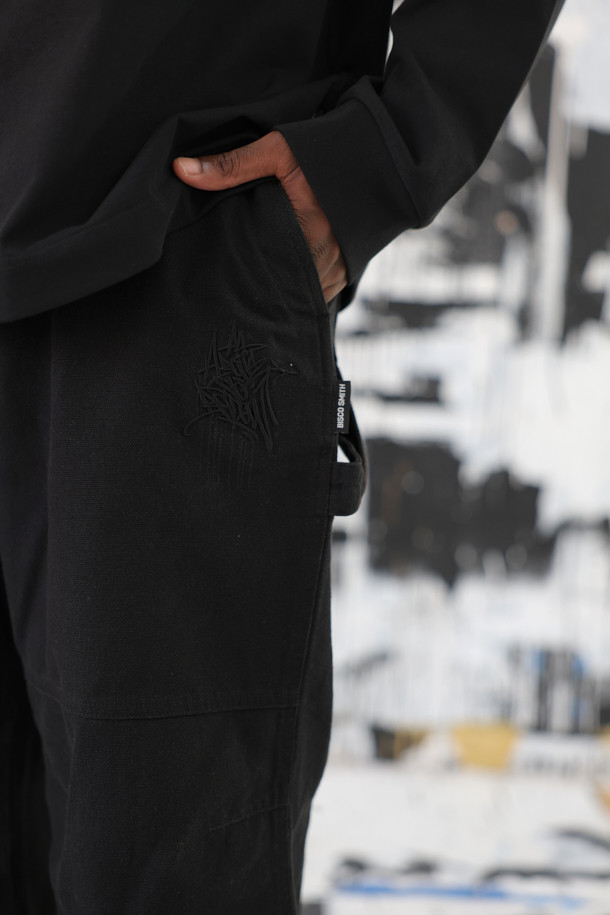 **BISCO SMITH (비스코 스미스) 블랙 코튼 카펜터 팬츠**

BISCO SMITH (비스코 스미스) 블랙 코튼 카펜터 팬츠는 스트릿 스타일을 기반으로, 워크웨어와 캐주얼 무드를 더한 긴 기장의 와이드핏 면 바지입니다. 무릎 부분의 파라슈트 레이어 디자인과 BISCO SMITH 'AsAbove' 자수 디테일이 특징입니다. 고밀도 코튼 소재를 사용하여 튼튼하며, 두꺼운 두께감으로 제작되었습니다. 편안하면서도 개성 있는 스타일을 연출하기에 좋은 아이템입니다.
