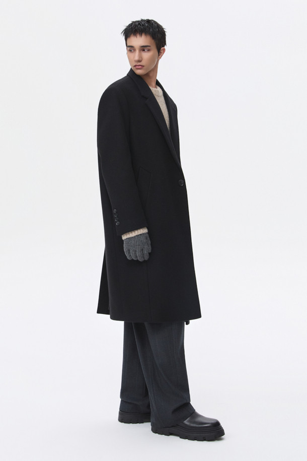 남성용 블랙 오버사이즈 핏 노치드 라펠 코트입니다. 가을, 겨울 시즌에 어울리는 두꺼운 두께감으로, 울, 나일론, 캐시미어 혼방 소재로 제작되어 부드러운 촉감과 보온성을 제공합니다. 미니멀, 클래식 스타일을 기반으로 하여 출근룩, 오피스룩, 모임룩 등 다양한 TPO에 활용 가능합니다. 싱글 버튼 여밈 방식과 롱 기장, 긴 소매 디자인으로 시크한 매력을 더하며, 오버핏으로 편안한 착용감을 선사합니다.
